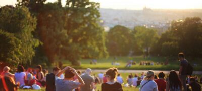 People sitting in groups together in a public garden in the sunshine.